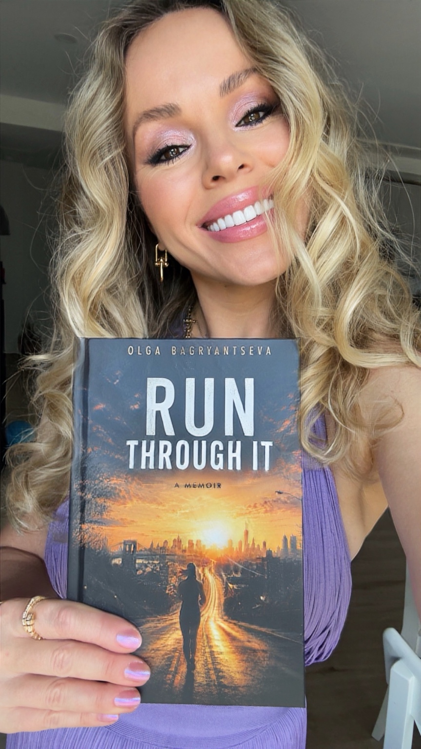 Olga Bagryantseva smiling and holding her memoir Run Through It